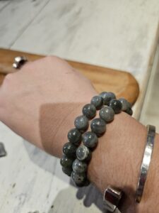 Bracelets en pierre gris-bleu autour du poignet, avec une peau montrant une swatch et un bracelet argenté. AuTroisièm'Oeil.