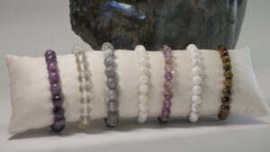 Bracelets de perles colorées alignés sur un coussinet blanc, mettant en valeur AuTroisièm’Oeil.
