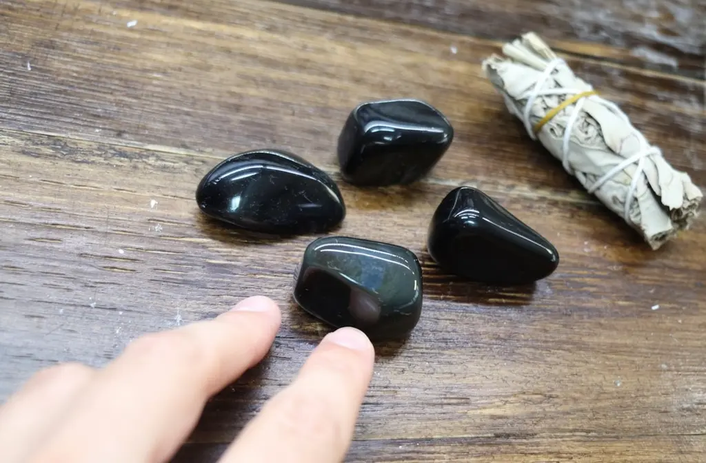 Pierres d'obsidienne noire polies posées sur un autel en bois sombre, utilisées comme pierres de protection contre les mauvaises énergies.