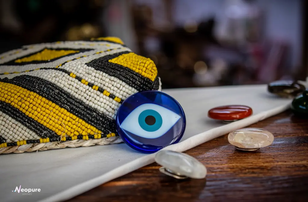 Pochette perlée et cristaux de protection contre le mauvais œil disposés sur un tissu blanc.